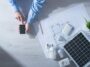 Man using a mobile touch screen smart phone next to a solar panel, a set of CFL lamps and a house project, energy saving concept